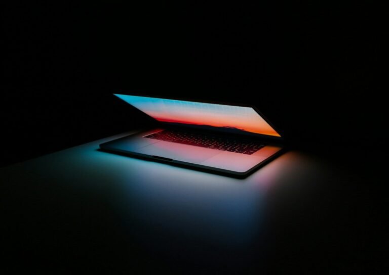 Notebook com tela iluminada em ambiente escuro.