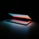 Notebook com tela iluminada em ambiente escuro.