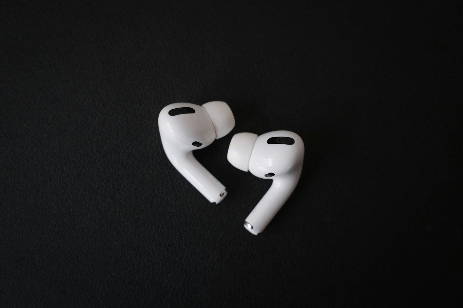 Fones de ouvido sem fio brancos sobre fundo preto, tecnologia de áudio portátil.