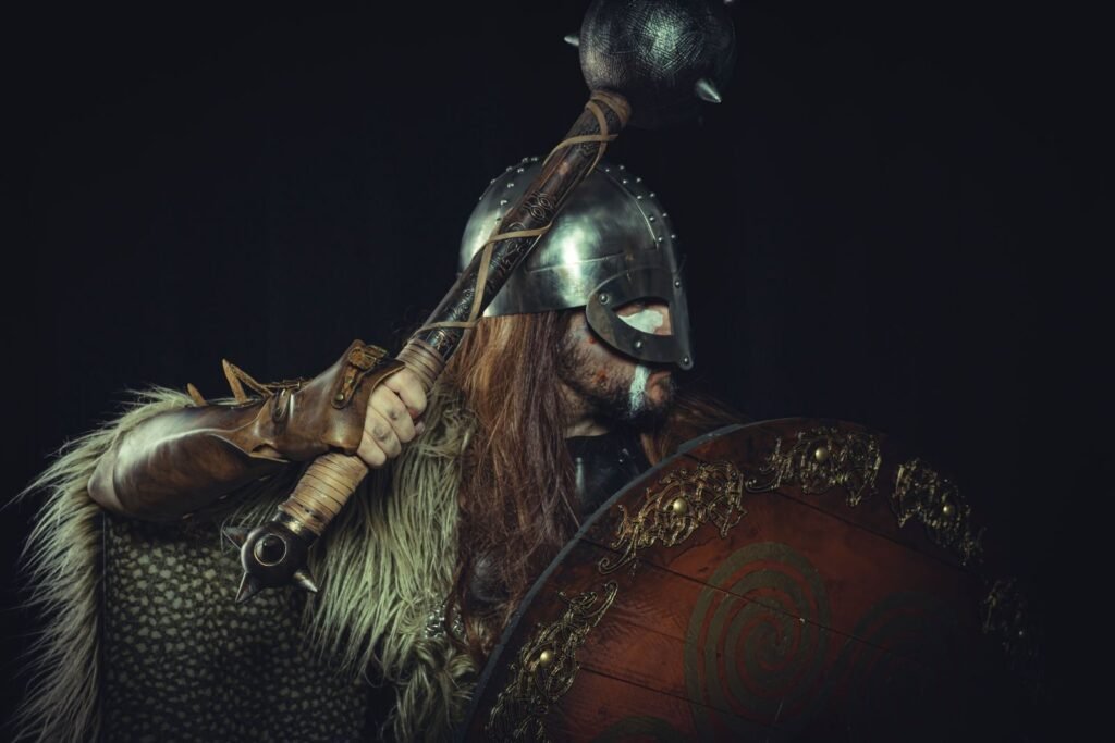 A fierce Viking warrior posing with a shield and bludgeon, wearing traditional armor.