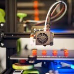 Detailed view of a 3D printer in action, fabricating small plastic pieces indoors.