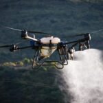 A drone disperses chemicals over crops in an agricultural field, enhancing productivity.