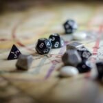 Focus on black and white polyhedral dice scattered on a board game map, suggesting strategy and chance.